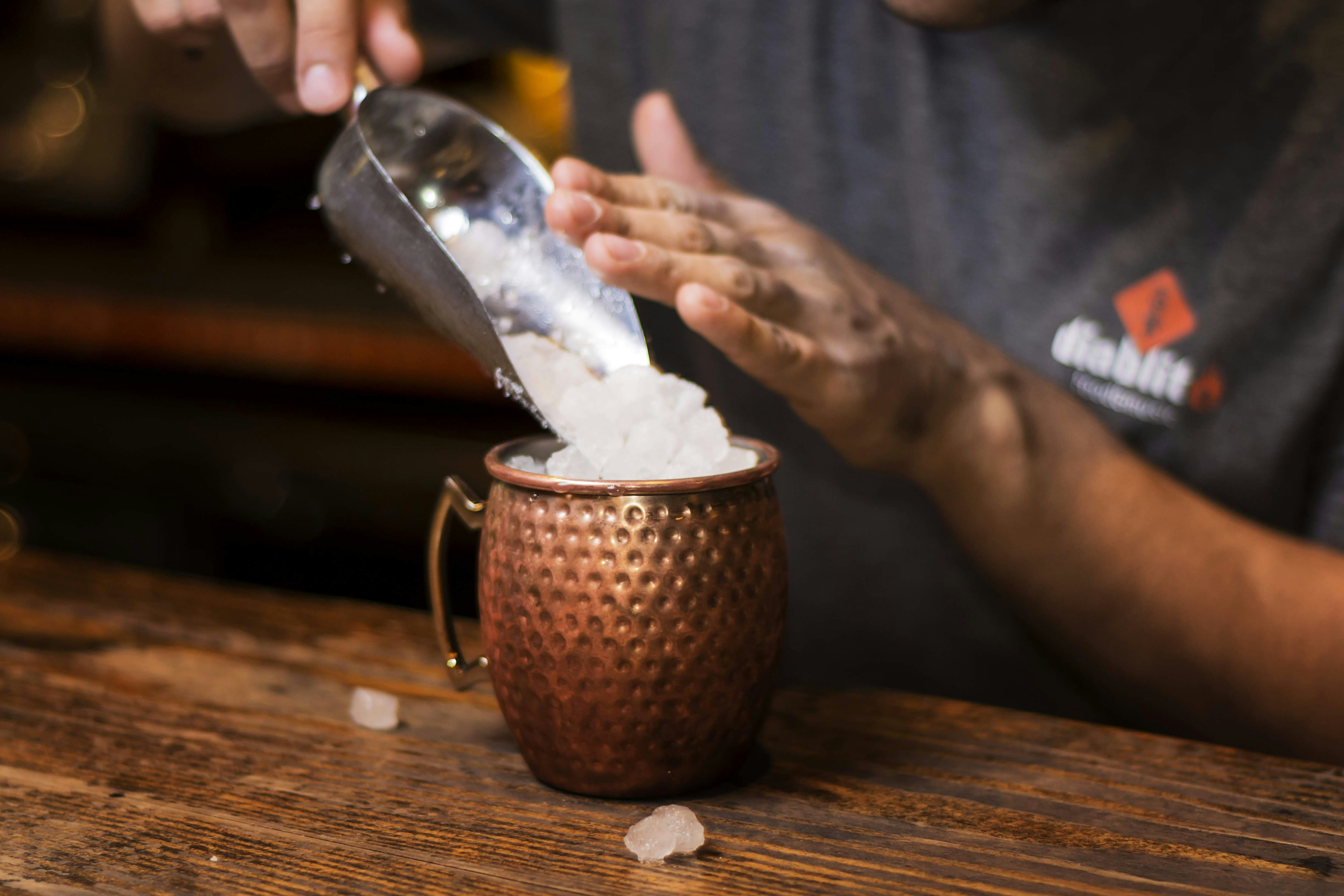 person pouring white powder on brown ceramic mug