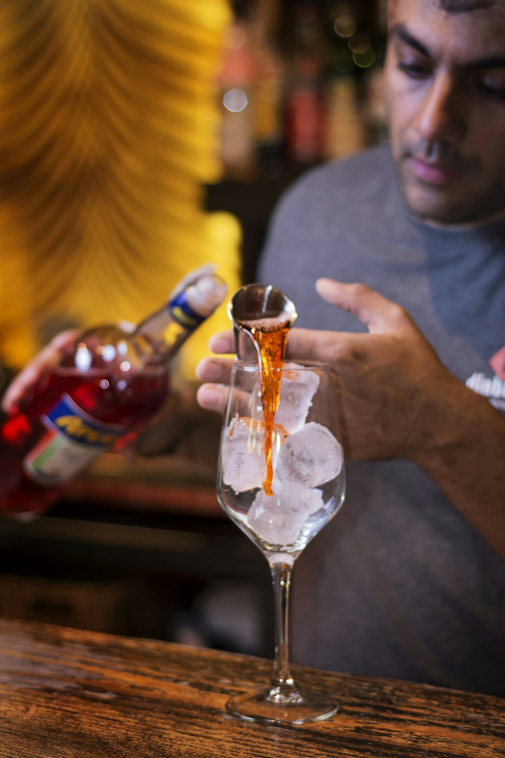 man in gray crew neck t-shirt holding clear glass bottle