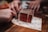 Close-up of hands collaborating over printed game materials on a wooden table.