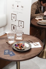 clear drinking glass beside blue ceramic plate on brown wooden table