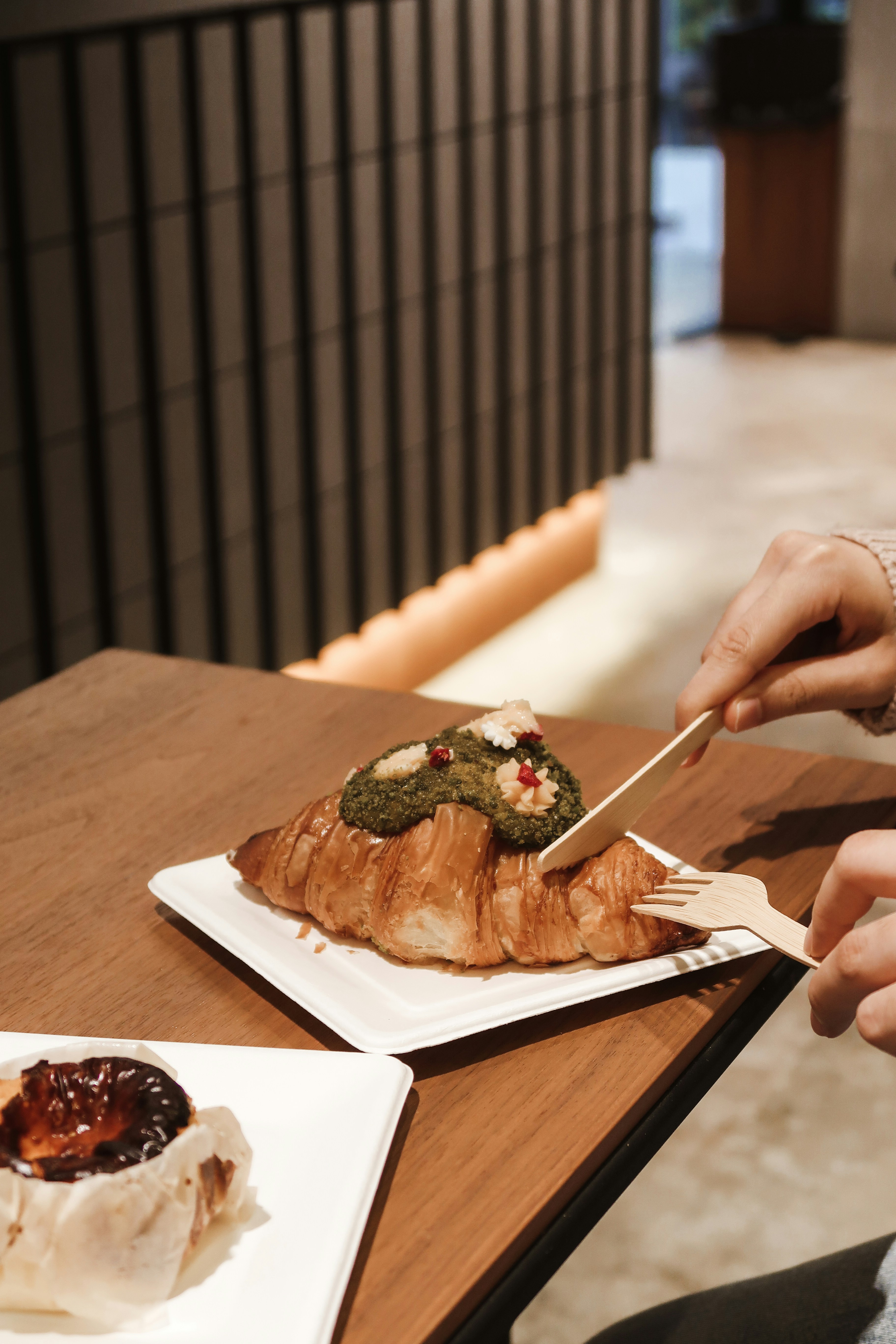 person holding fork and knife slicing meat on white ceramic plate