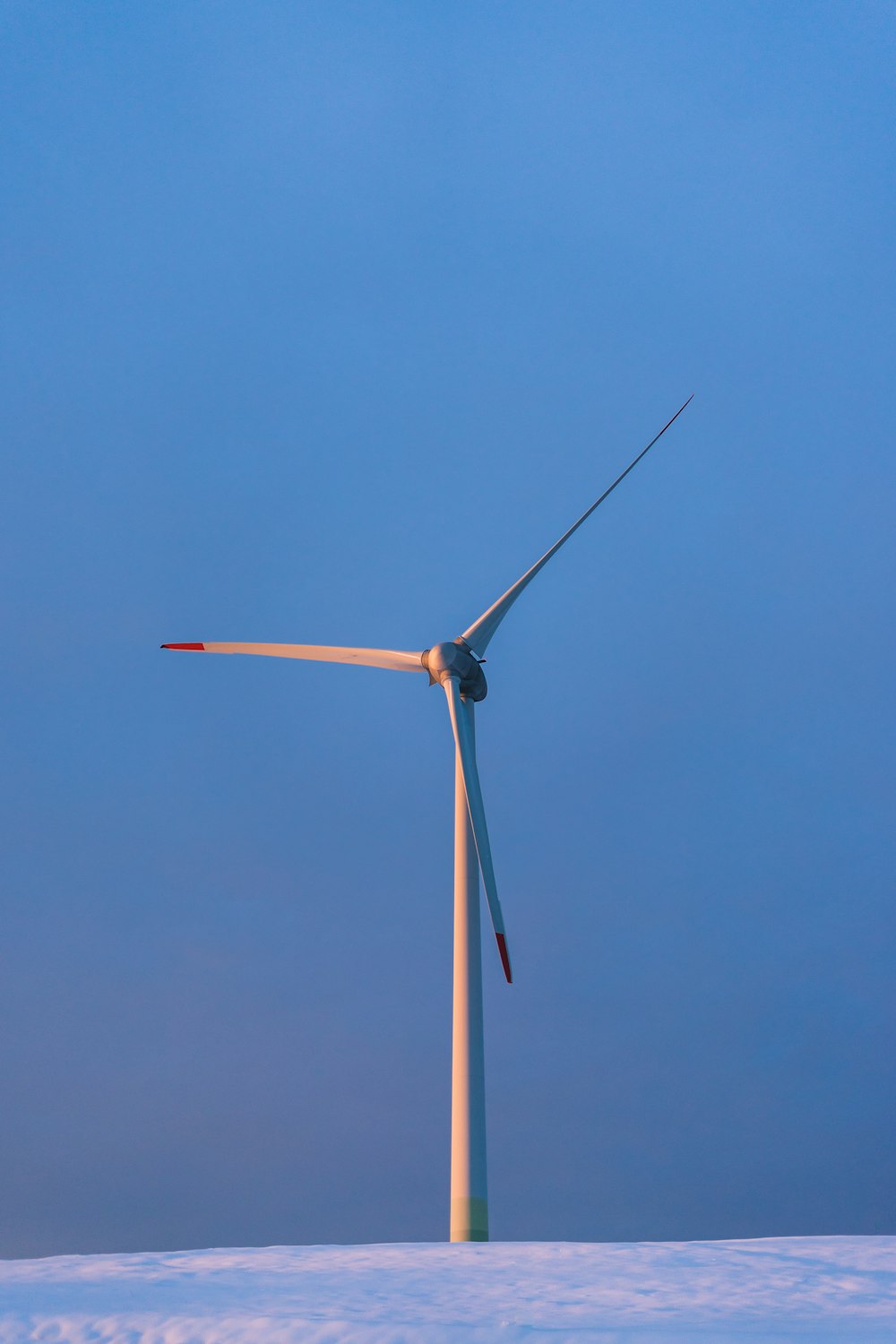 white wind turbine under blue sky during daytime