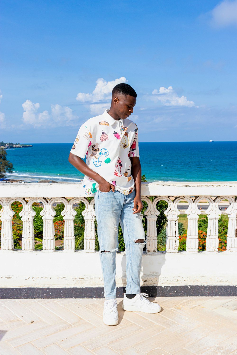 man in white and red floral crew neck t-shirt standing on white concrete fence near near near near near