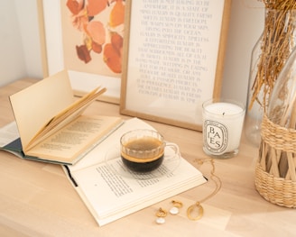 white ceramic mug beside white book on brown wooden table