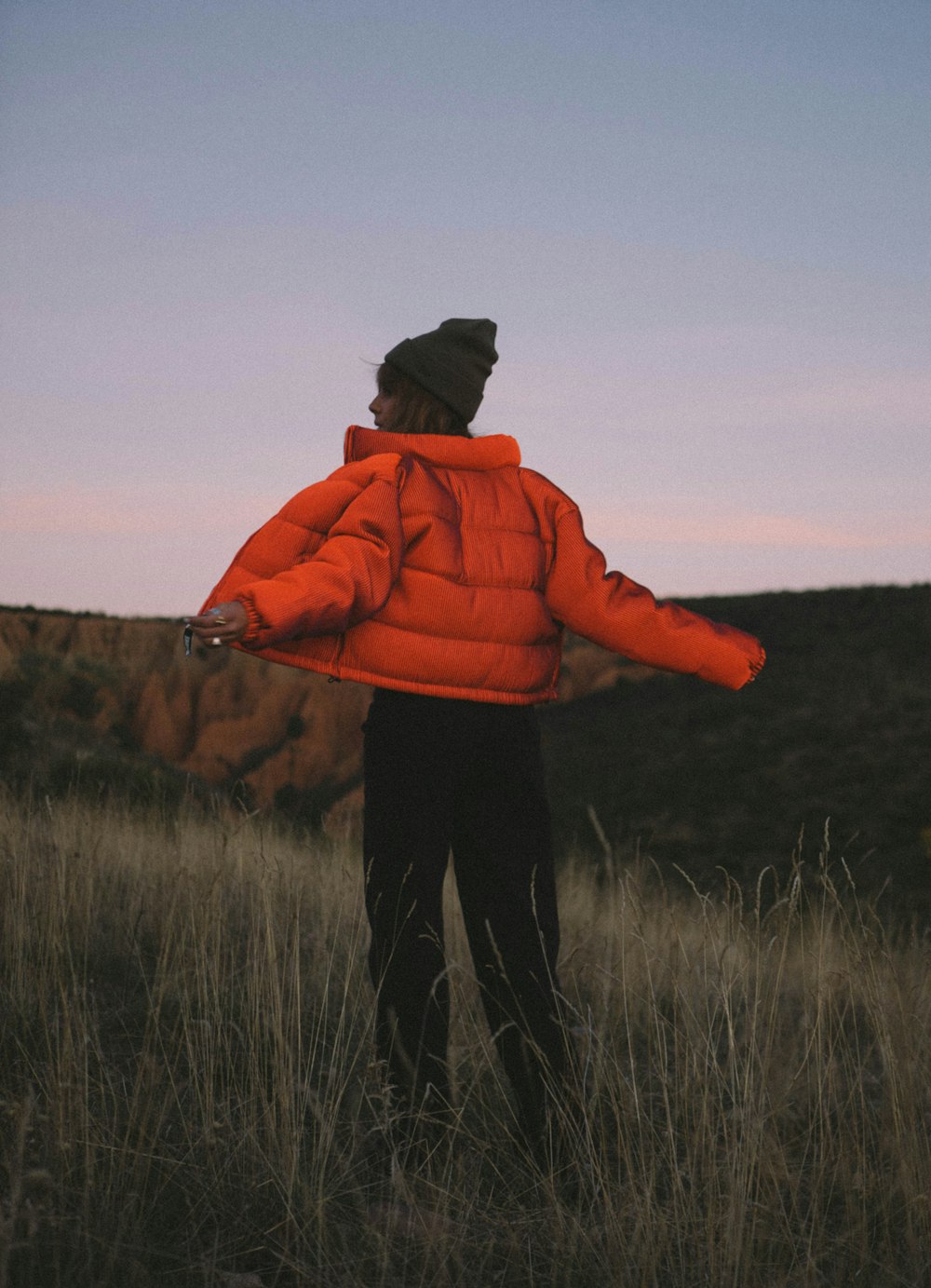 person in orange hoodie standing on green grass field during daytime