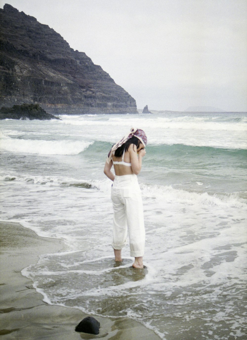 woman in white spaghetti strap dress standing on seashore during daytime