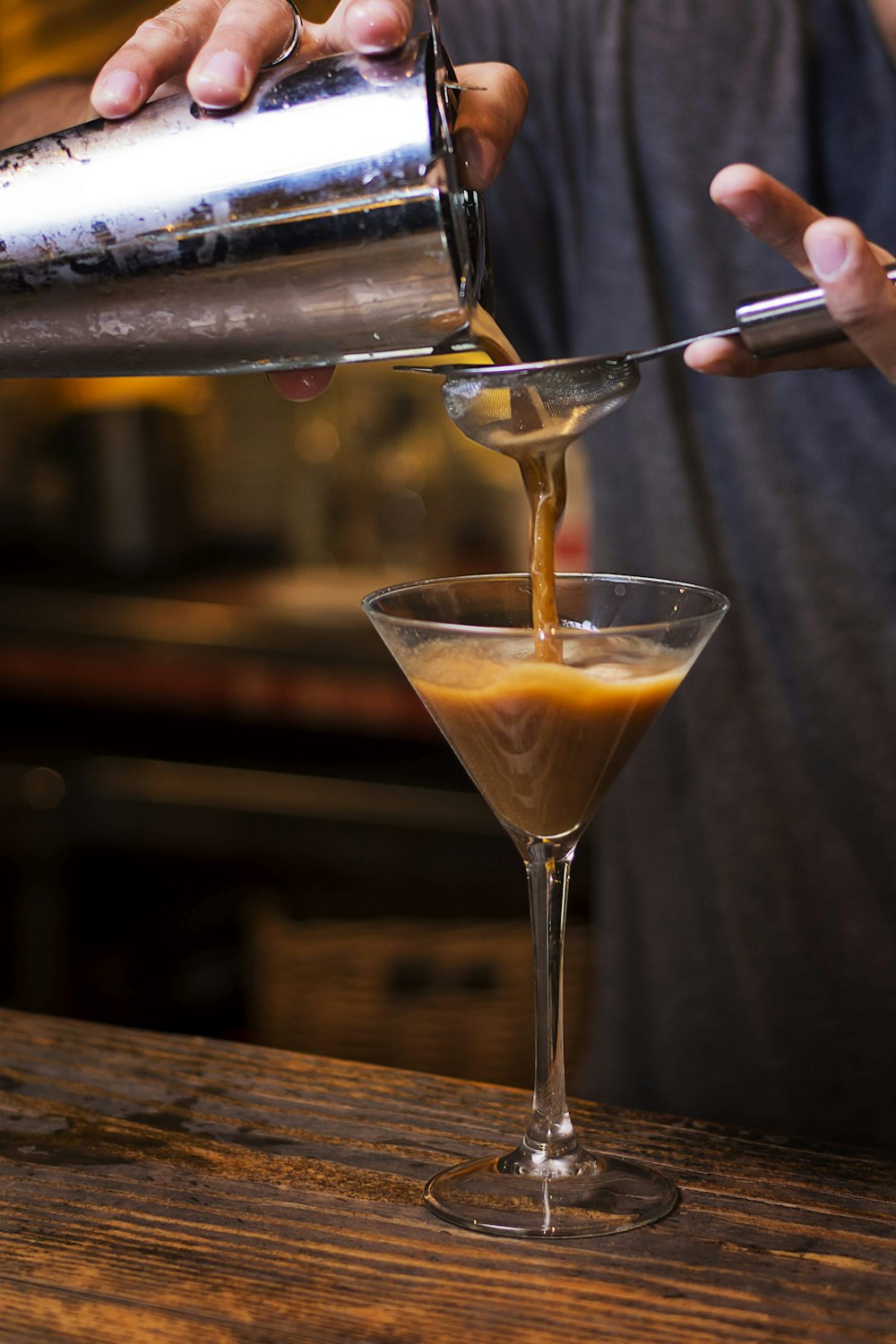 person pouring yellow liquid on cocktail glass