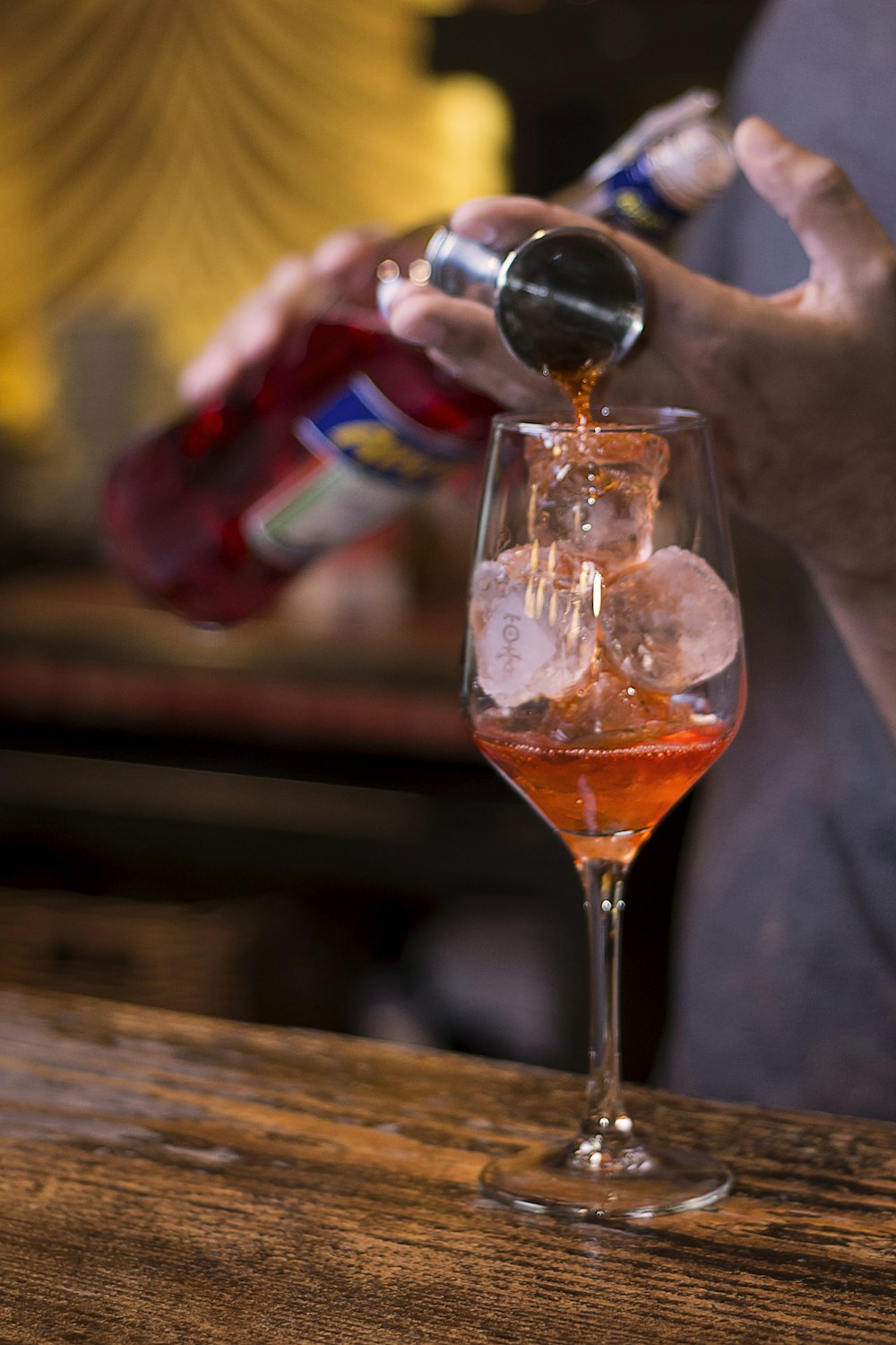 person pouring beverage on clear wine glass