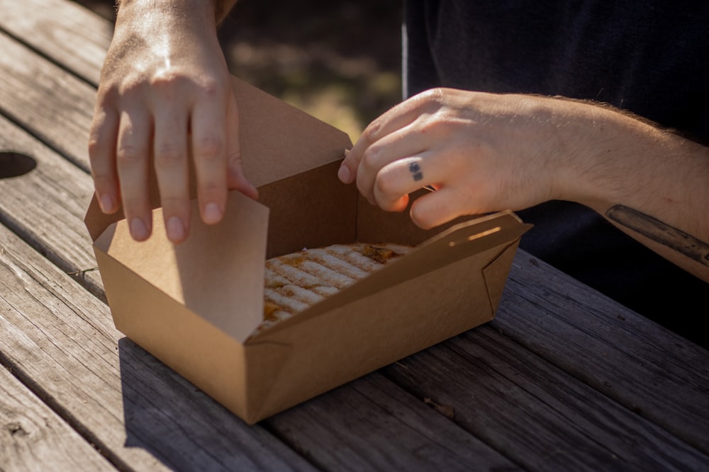 Persona sosteniendo una caja de cartón marrón