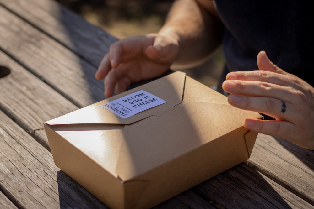 person holding brown cardboard box