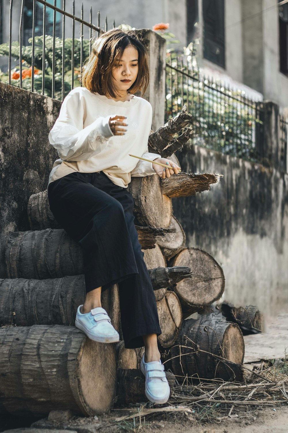 woman in white long sleeve shirt and black skirt sitting on brown wooden log