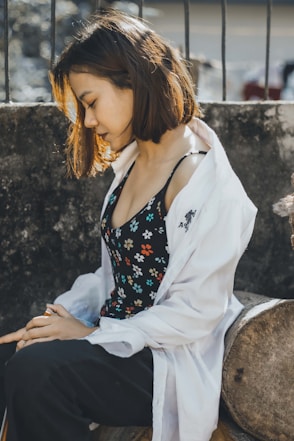woman in black and white floral spaghetti strap top and white pants sitting on rock