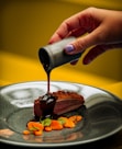 person pouring chocolate on chocolate cake