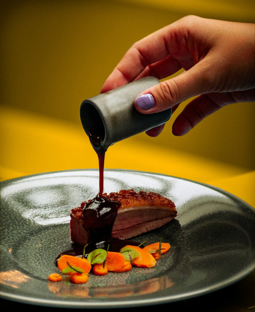 person pouring chocolate on chocolate cake