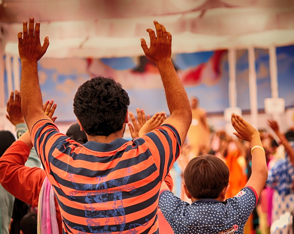 man in black white and red striped polo shirt raising his hands