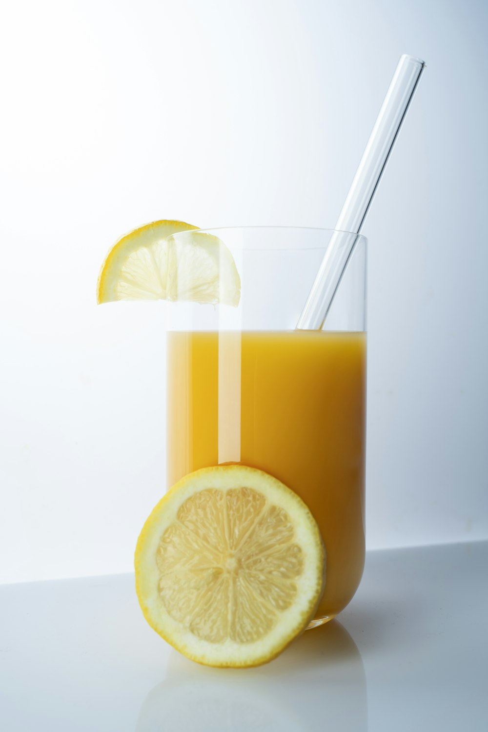 klares Trinkglas mit gelber Flüssigkeit und in Scheiben geschnittener Zitrone