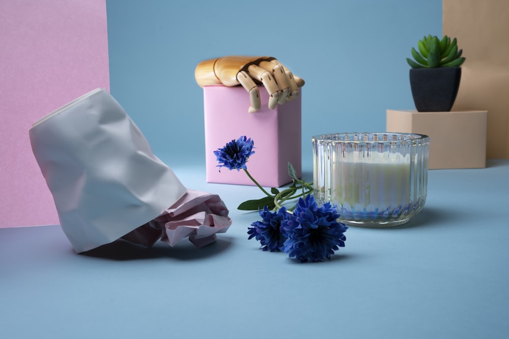 a vase with flowers, a candle, and a bag on a table