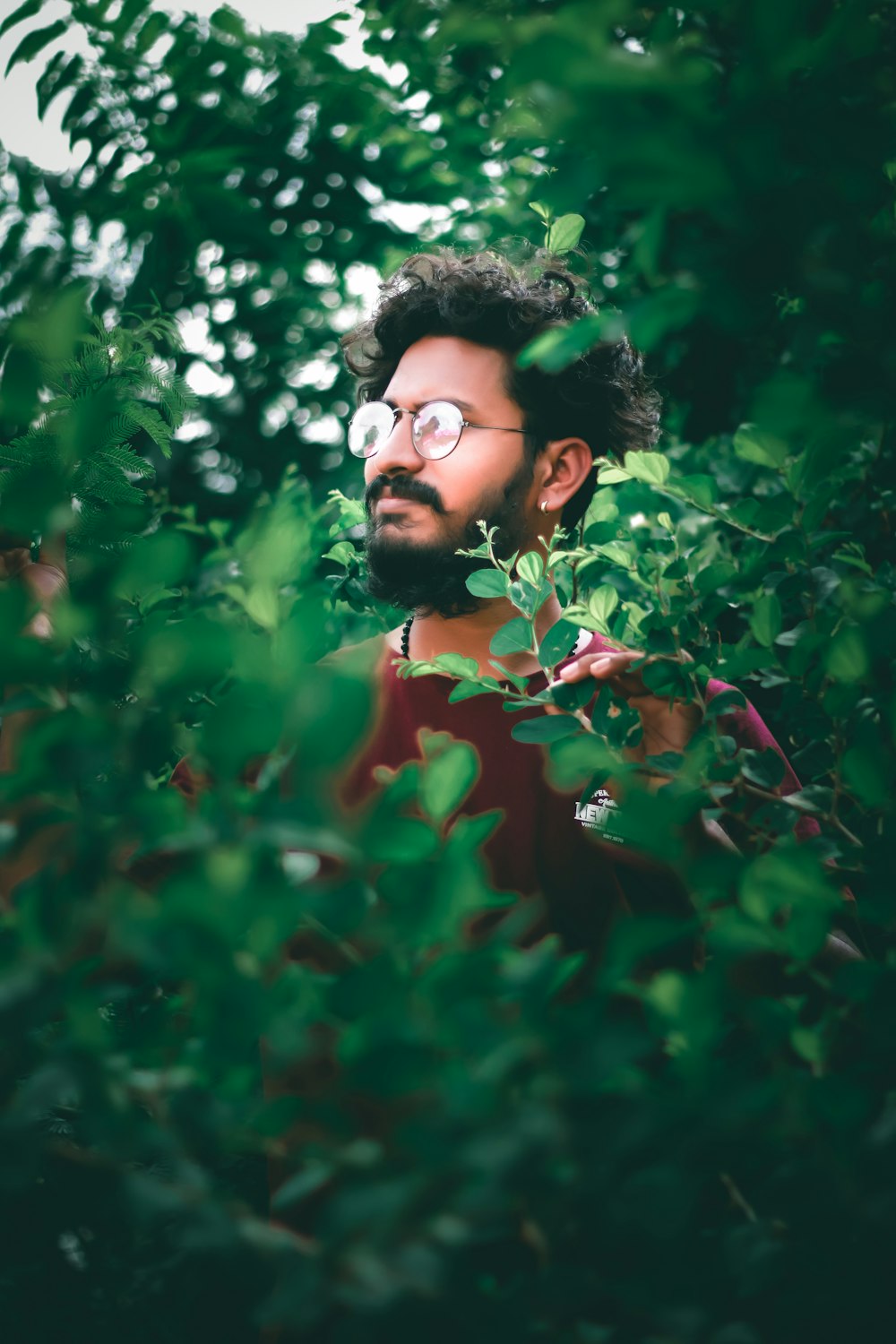 woman in red shirt standing near green plants during daytime