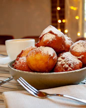 A cozy corner of nubedorada with golden pastry puffs steaming on a rustic wooden table.