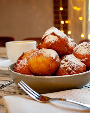 A cozy corner of nubedorada with golden pastry puffs steaming on a rustic wooden table.