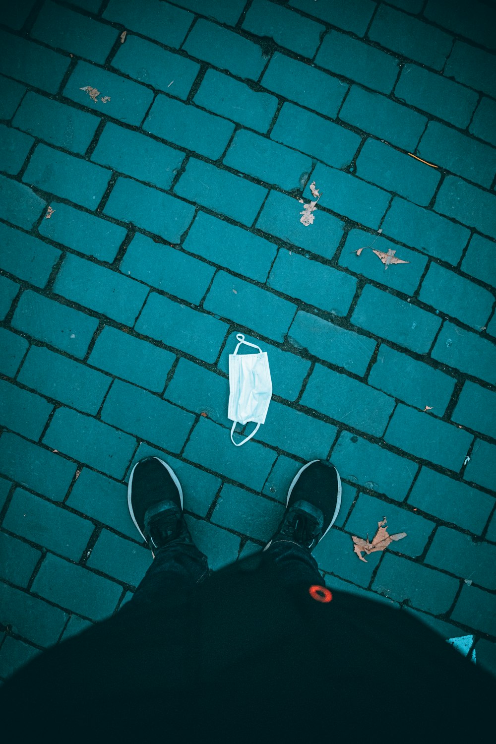 person in black pants and black shoes standing on brown brick floor