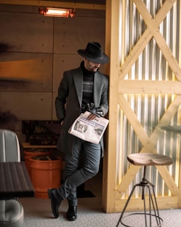 A fashionable man in a neutral-toned outfit, posing in a chic café.