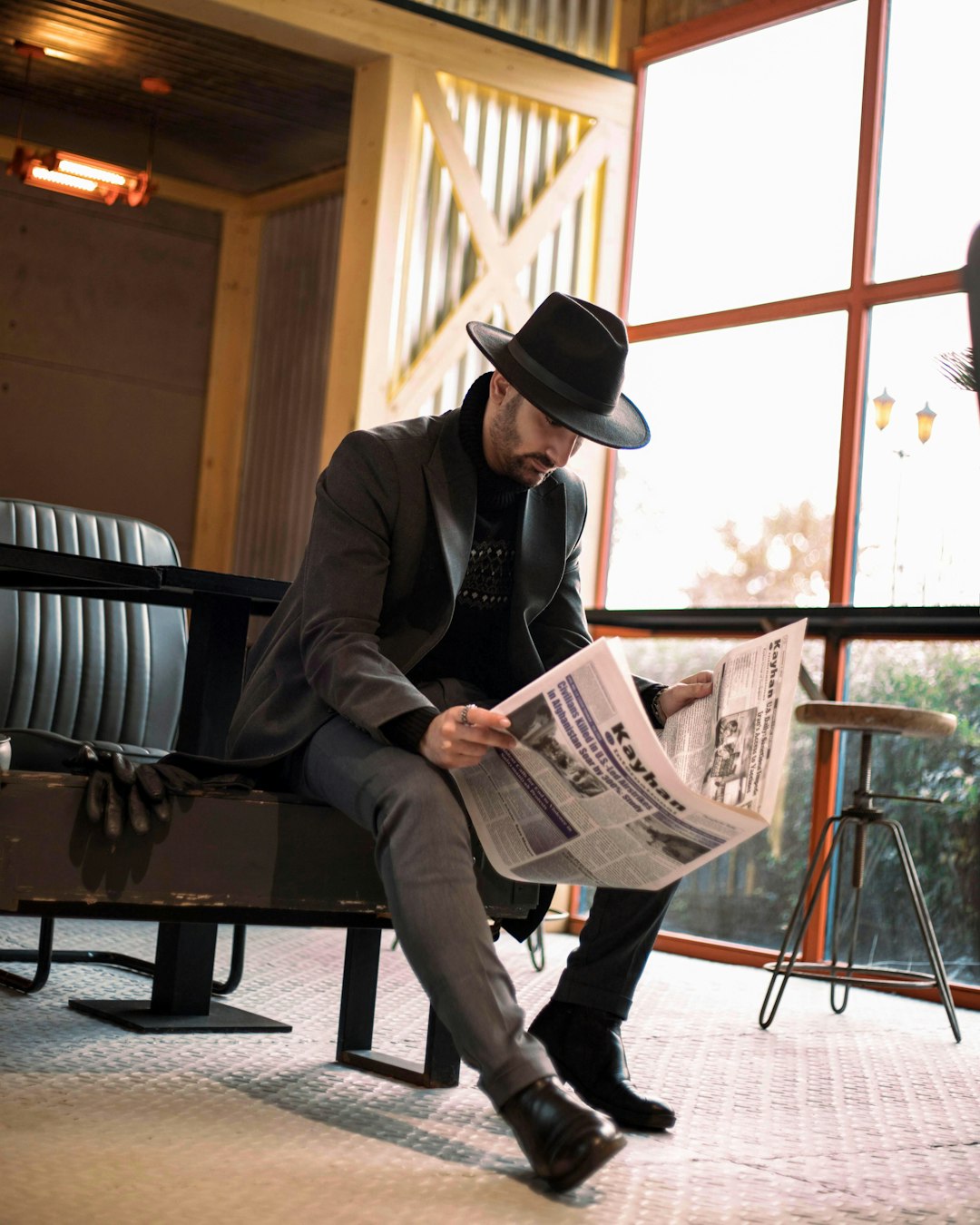 man in black suit jacket and black fedora hat reading newspaper