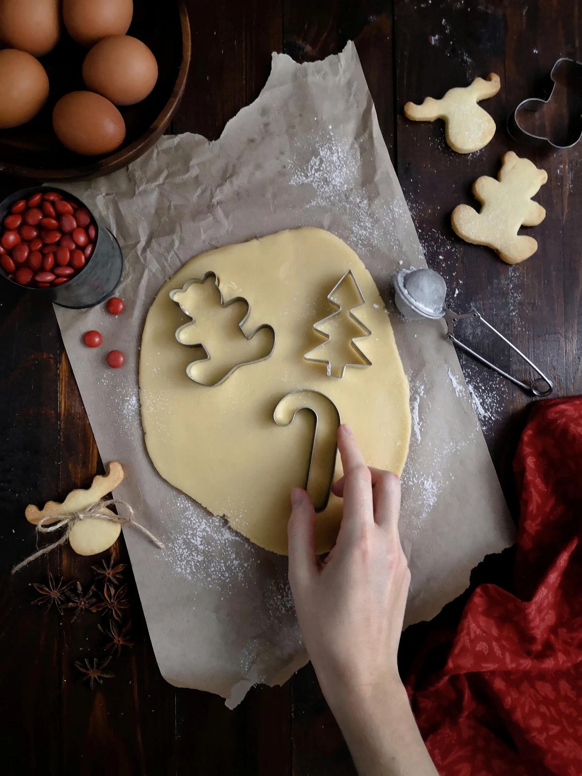 Assorted cookie cutters arranged on a flour-dusted surface with rolled dough