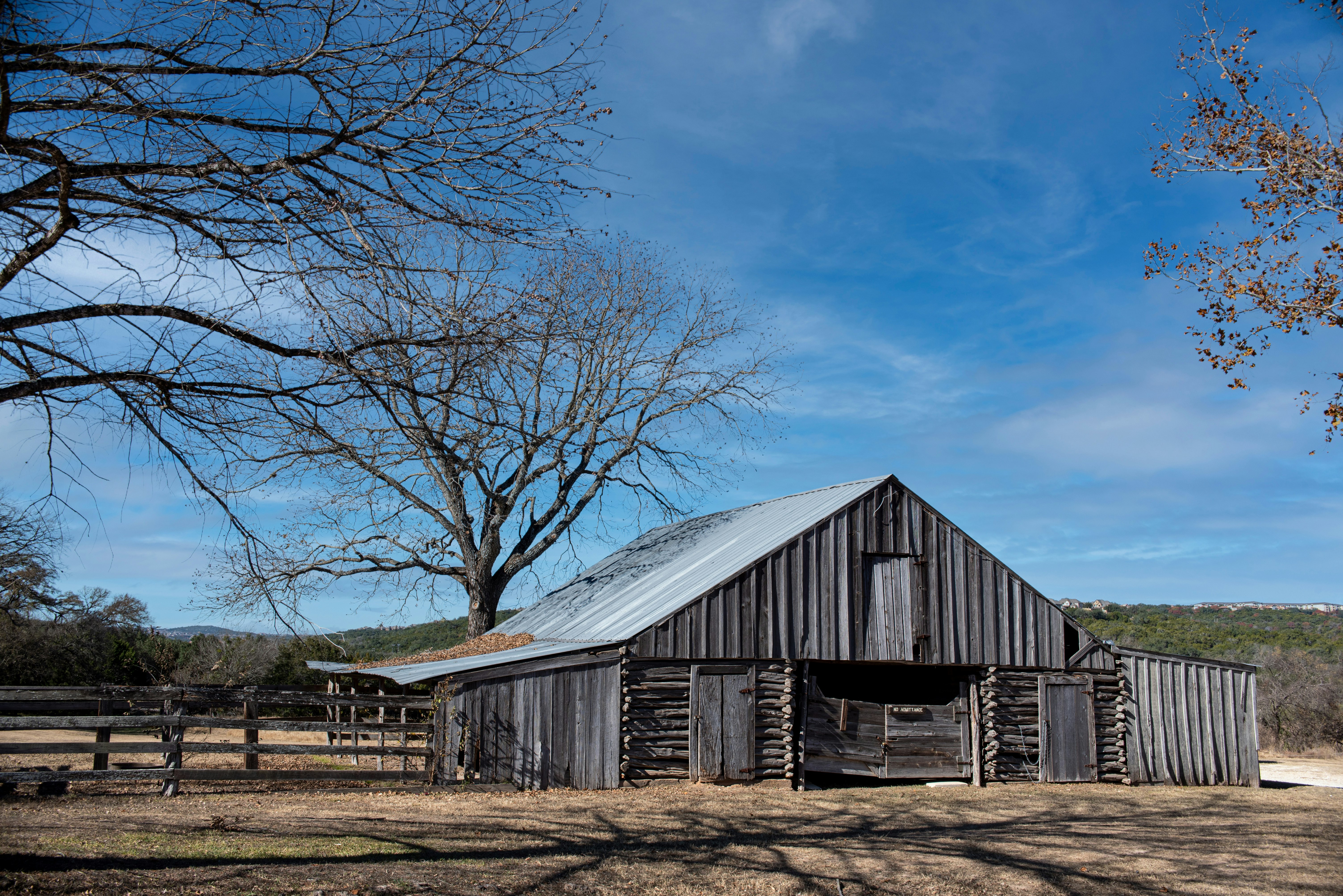 brown wooden house near bare trees under blue sky during daytime