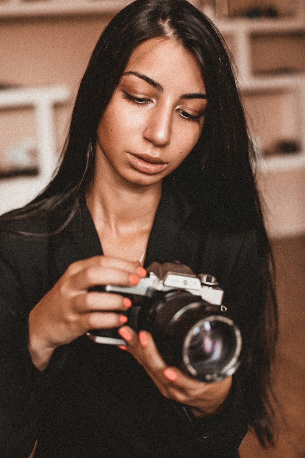 Frau in schwarzem Langarmhemd mit schwarzer und silberner DSLR-Kamera