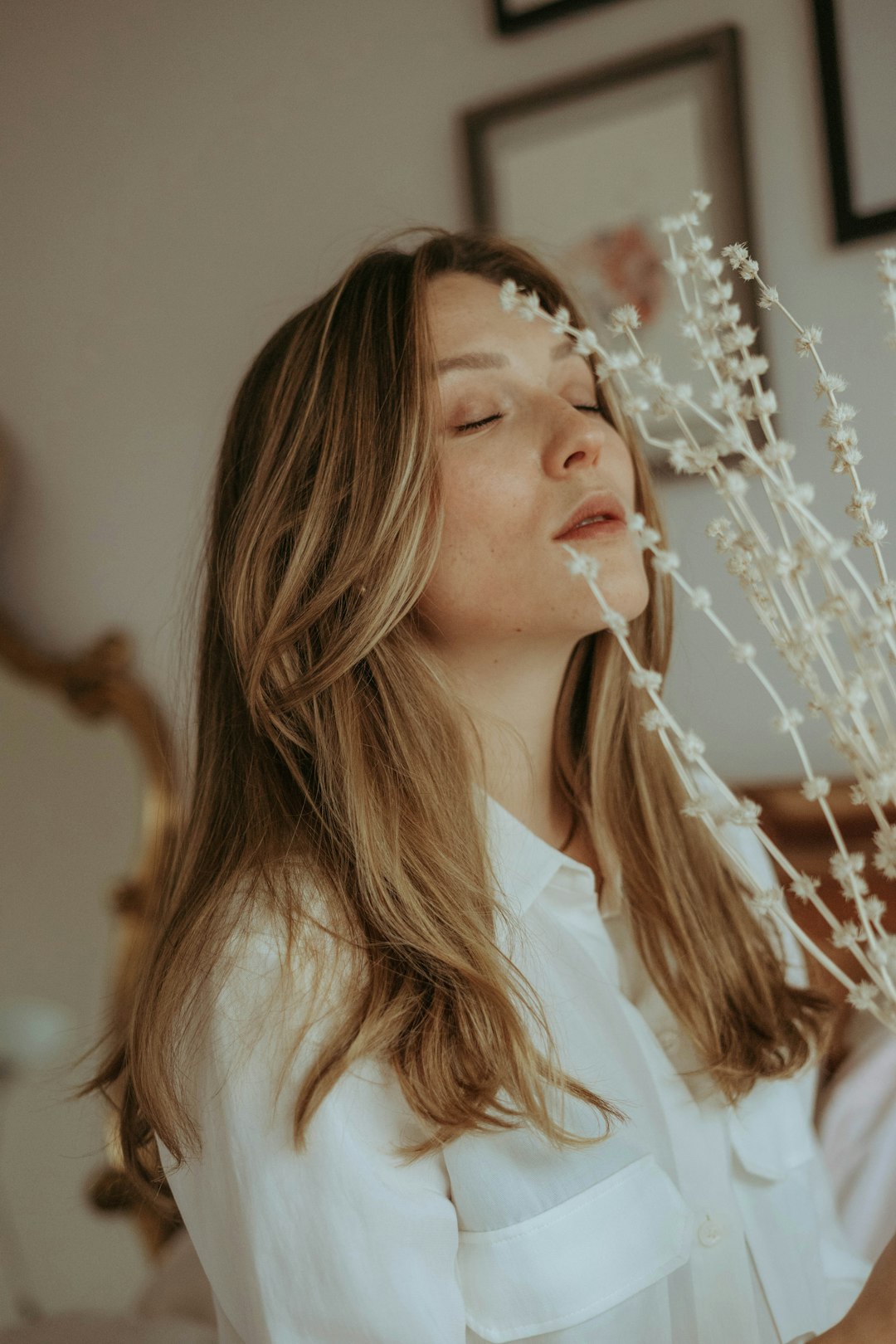 woman in white shirt blowing white dandelion