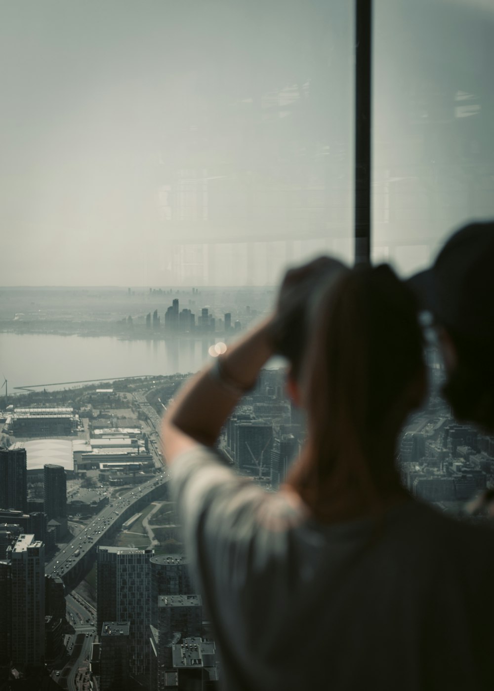 woman in white shirt taking photo of city skyline during daytime