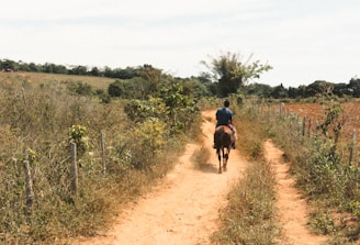 man in red shirt riding on bicycle on dirt road during daytime