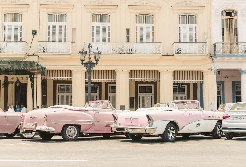 pink and white chevrolet camaro parked in front of beige concrete building during daytime