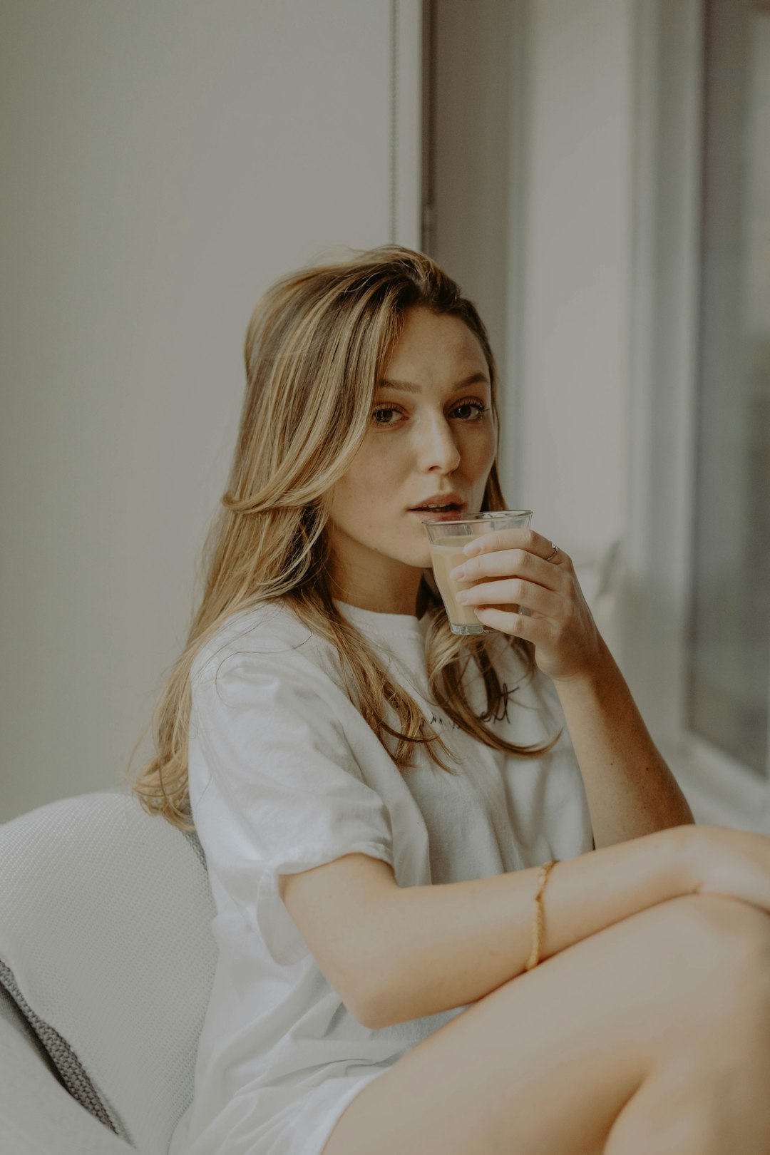 woman in white long sleeve shirt holding white ceramic mug