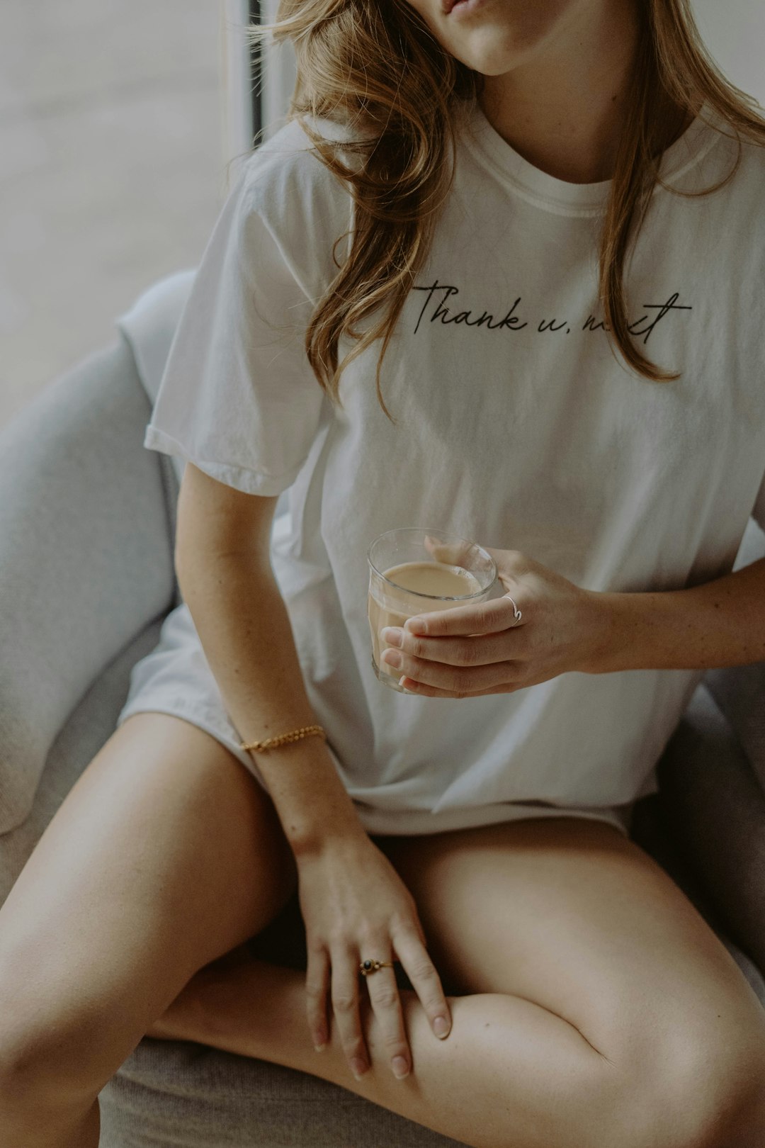 woman in white crew neck t-shirt holding clear drinking glass