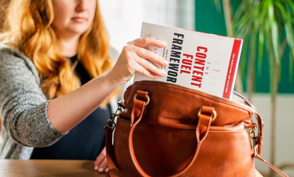 woman holding brown leather handbag