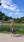 Smiling woman standing proudly in front of her newly built backyard ADU with lush greenery around.