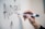 A hand is holding a black dry erase marker and writing the word 'AUDIENCE' on a whiteboard.