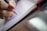 A close-up of a hand holding a sleek pen while writing in a notebook.