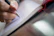 A close-up of a hand writing in a spiritual-themed notebook with a white background.