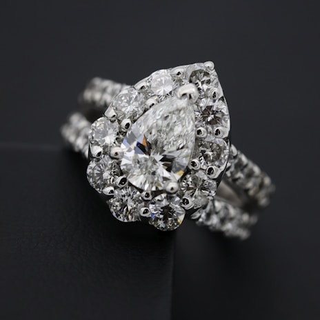 A close-up of a delicate platinum ring showcasing a radiant natural diamond surrounded by intricate detailing.