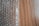 A sheet of transparent bubble wrap lies on a wooden surface, partially covering it. The bubble wrap consists of evenly spaced, raised circular bubbles that create a pattern of repeating circles. The wooden surface has a light brown color with visible grain patterns.
