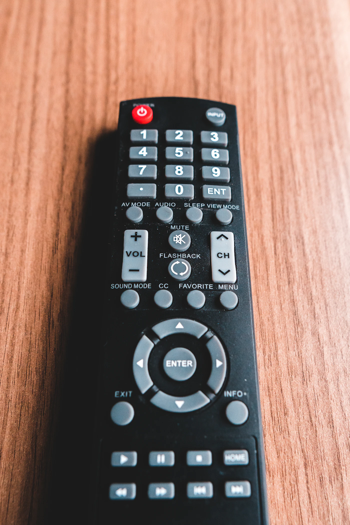 A black remote control on a wooden table