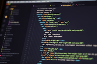 A close-up of a computer screen displaying HTML code in a text editor. The code includes elements such as sections, headers, and paragraphs, with various class attributes for styling. The interface shows file tabs at the top, suggesting it's part of a larger project.
