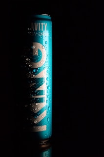 A tall, blue can with visible water droplets sits against a black background. The word 'KINGS' is prominently displayed in large white letters vertically along the can. The lighting creates a dramatic contrast, highlighting the texture of the droplets and the sleekness of the can.