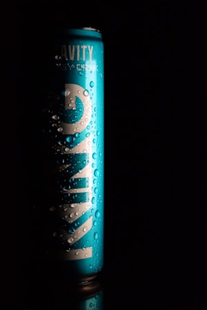 A tall, blue can with visible water droplets sits against a black background. The word 'KINGS' is prominently displayed in large white letters vertically along the can. The lighting creates a dramatic contrast, highlighting the texture of the droplets and the sleekness of the can.