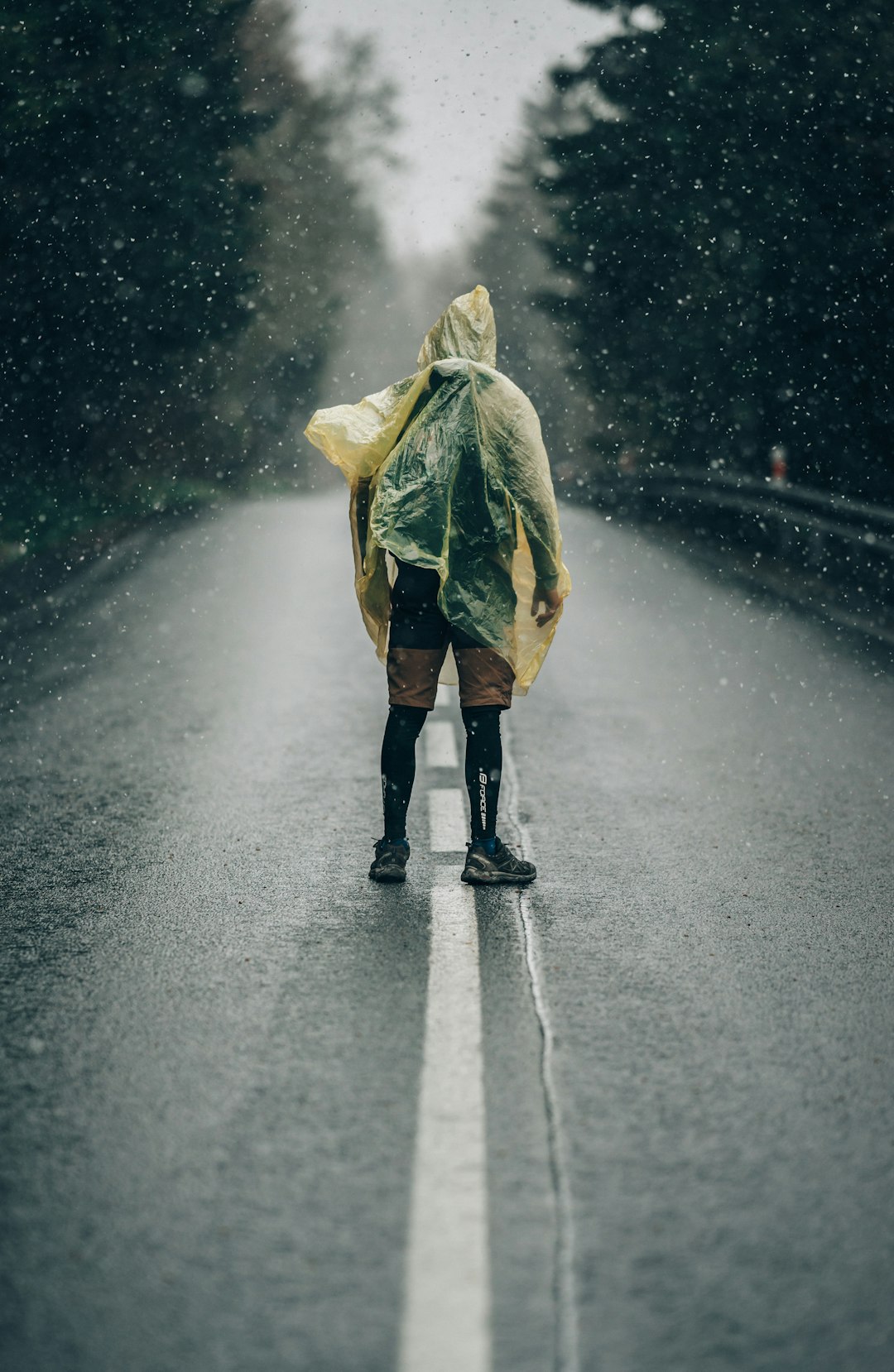 person in yellow rain coat walking on road during daytime
