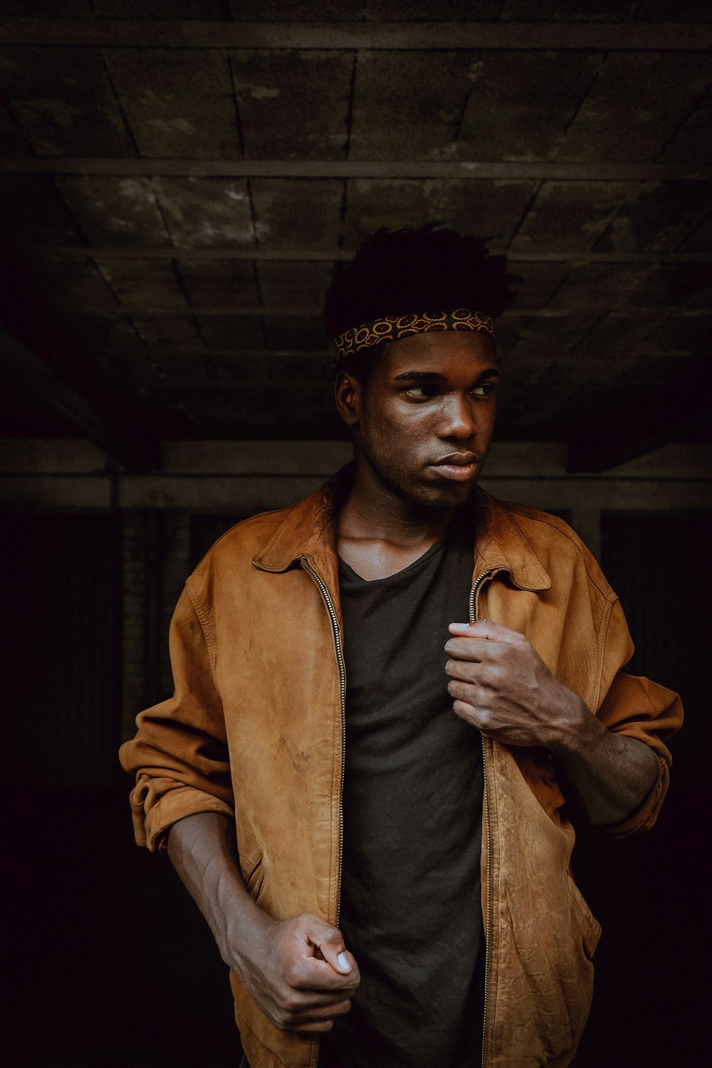 man in brown coat and black and white floral bandana