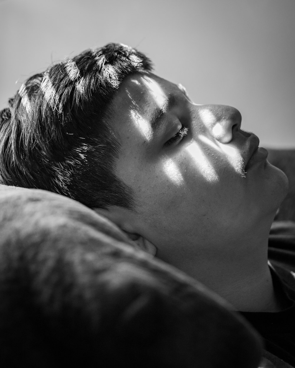 grayscale photo of man lying on bed